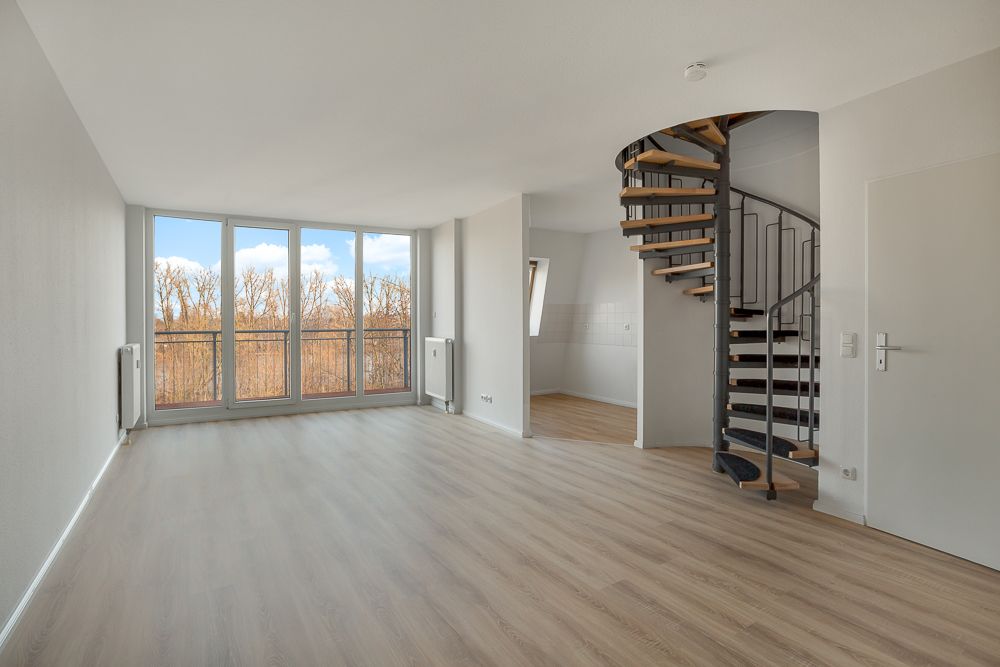 Helles Wohnzimmer mit großen Fenstern, Holzfußboden und Wendeltreppe.