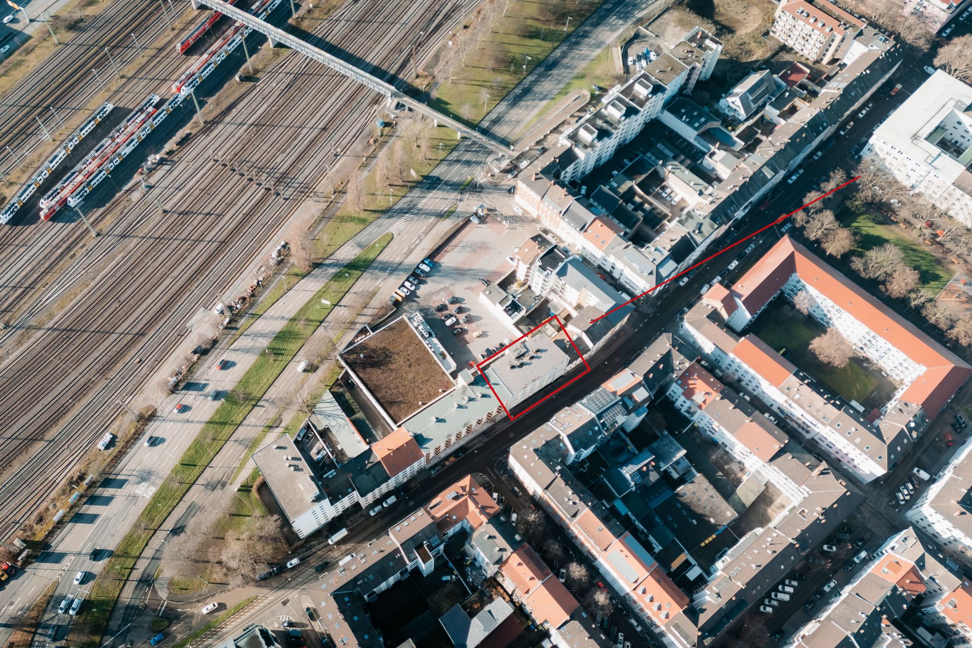 Luftbild einer Wohngegend neben Bahngleisen mit Häusern und Straßen.