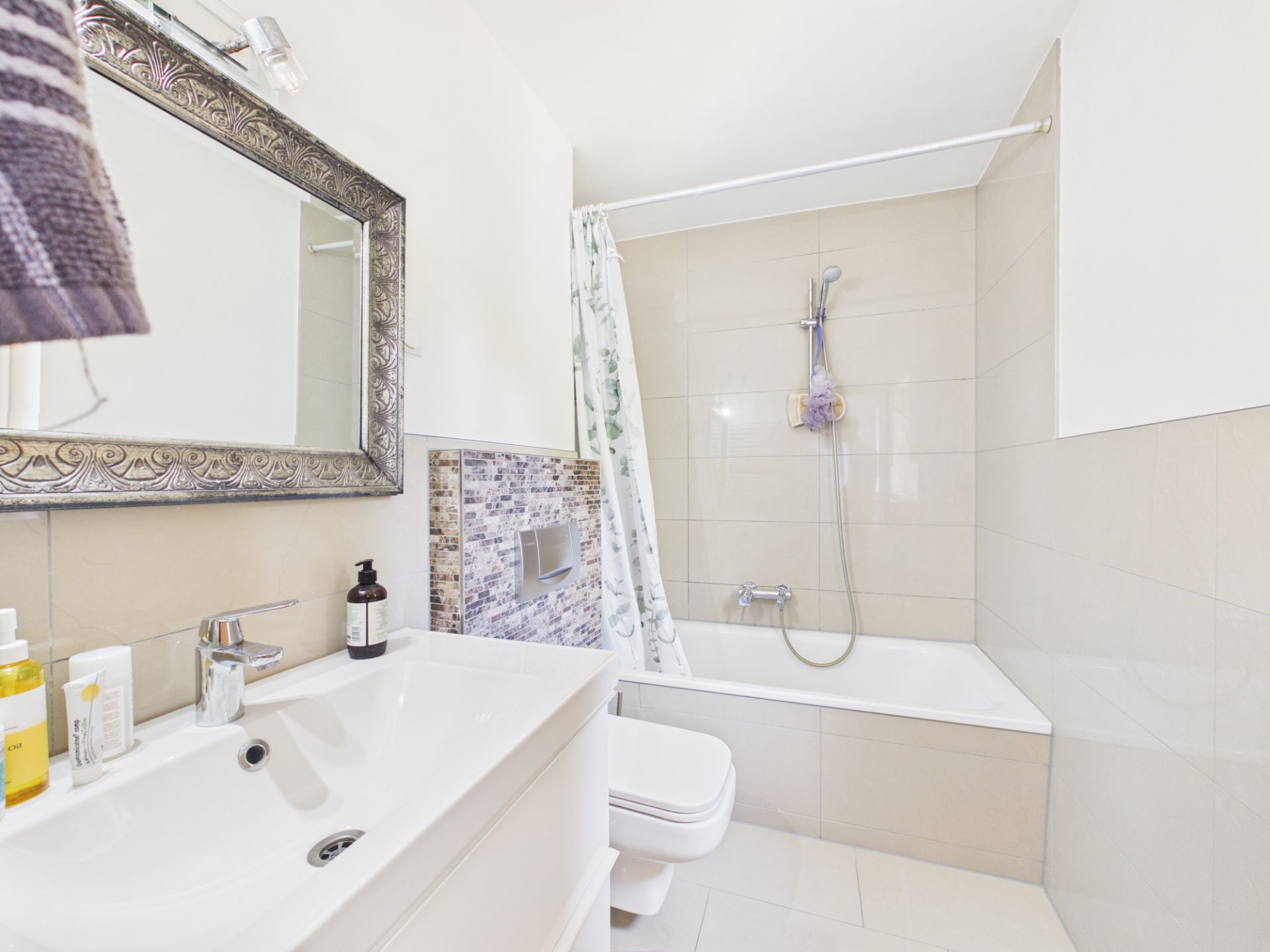 Modernes Badezimmer mit Waschbecken, Spiegel, Badewanne und Duschvorhang.