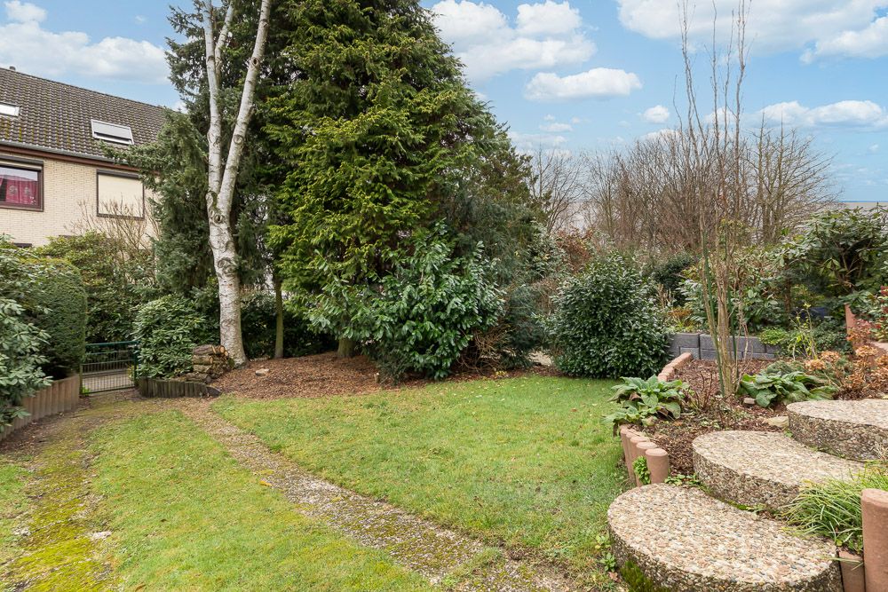 Gepflegter Garten mit Rasen, großen Bäumen und halbrunden Steinstufen.