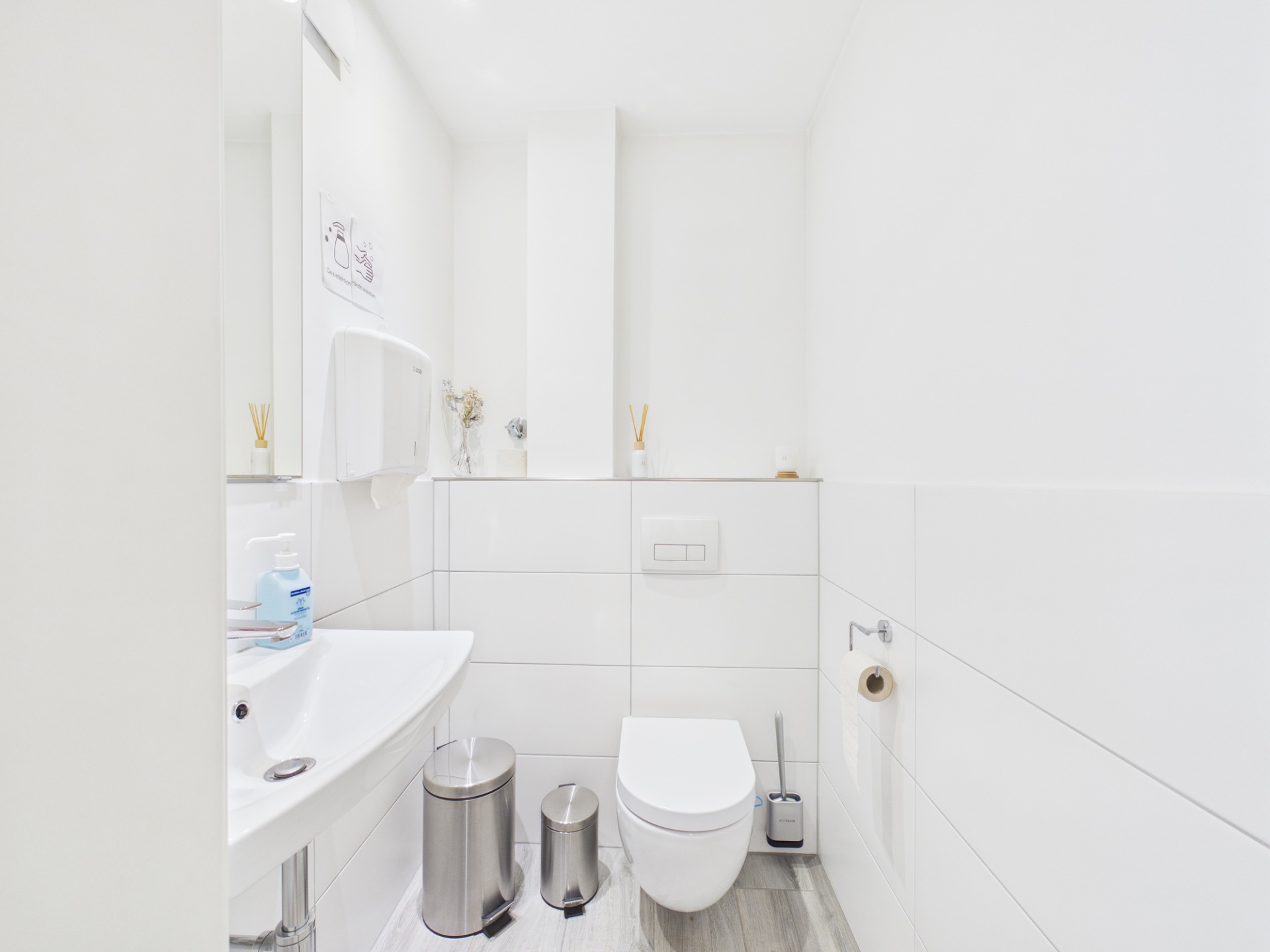 Helles, modernes Badezimmer mit WC, Waschbecken und zwei Mülleimern.