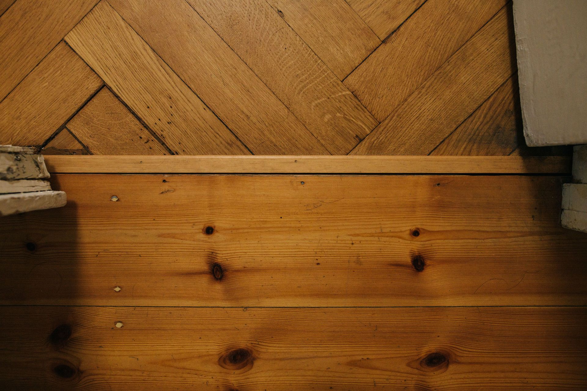 Detailansicht zweier unterschiedlicher Holzböden mit einer Trennleiste dazwischen.