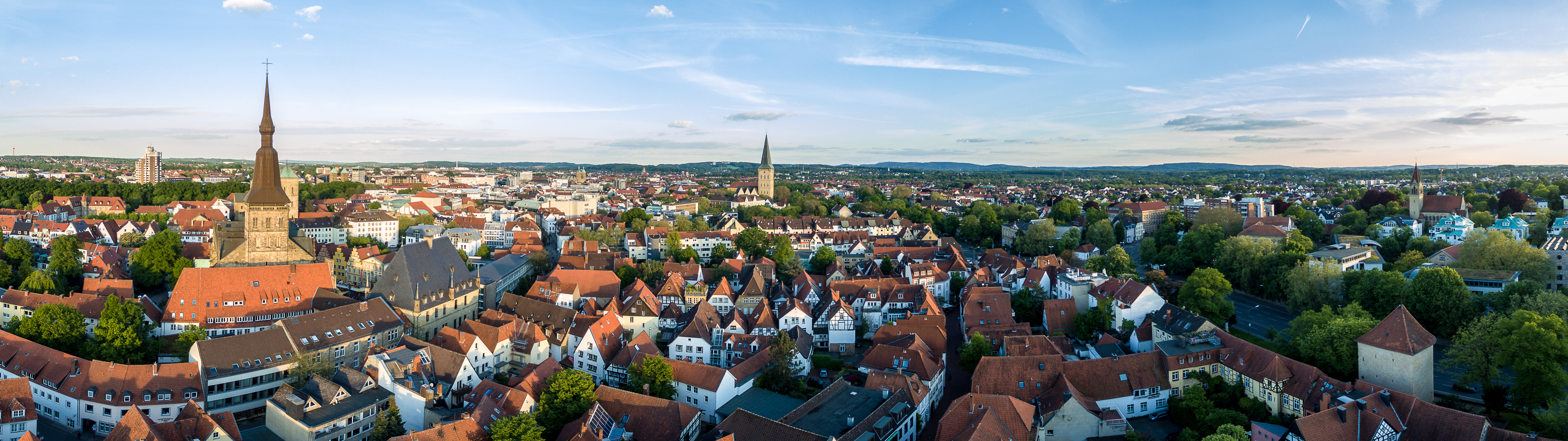Schmale gepflasterte Straße mit Wohnhäusern und geöffneten Fenstern an beiden Seiten bei Tageslicht.