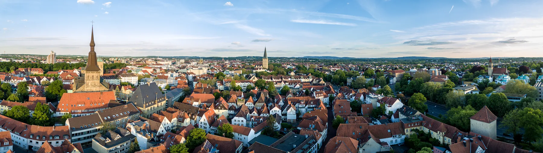 Schmale gepflasterte Straße mit Wohnhäusern und geöffneten Fenstern an beiden Seiten bei Tageslicht.