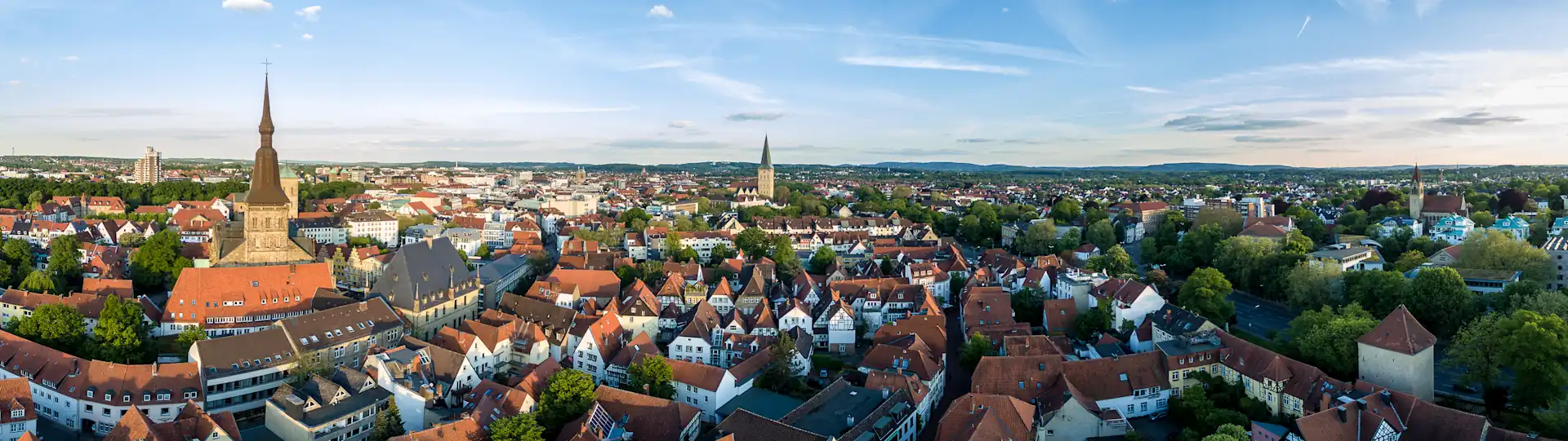 Schmale gepflasterte Straße mit Wohnhäusern und geöffneten Fenstern an beiden Seiten bei Tageslicht.