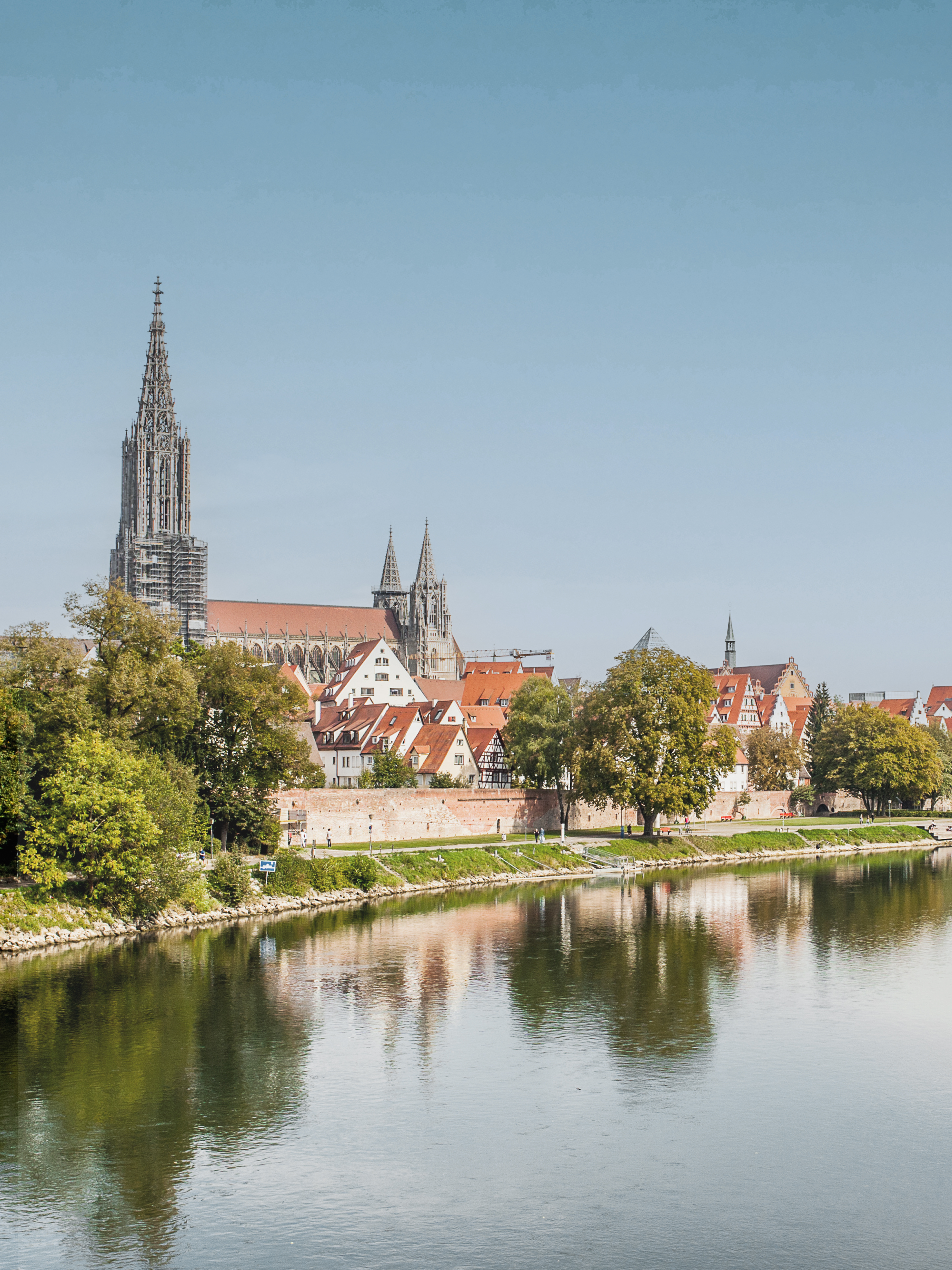 Blick auf eine Stadt mit Fluss, Bäumen und einer großen Kirche im Hintergrund.