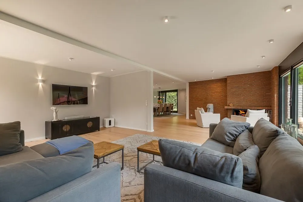 Großes Wohnzimmer mit zwei Sofas, Fernseher, Holzboden und Blick auf einen Essbereich.