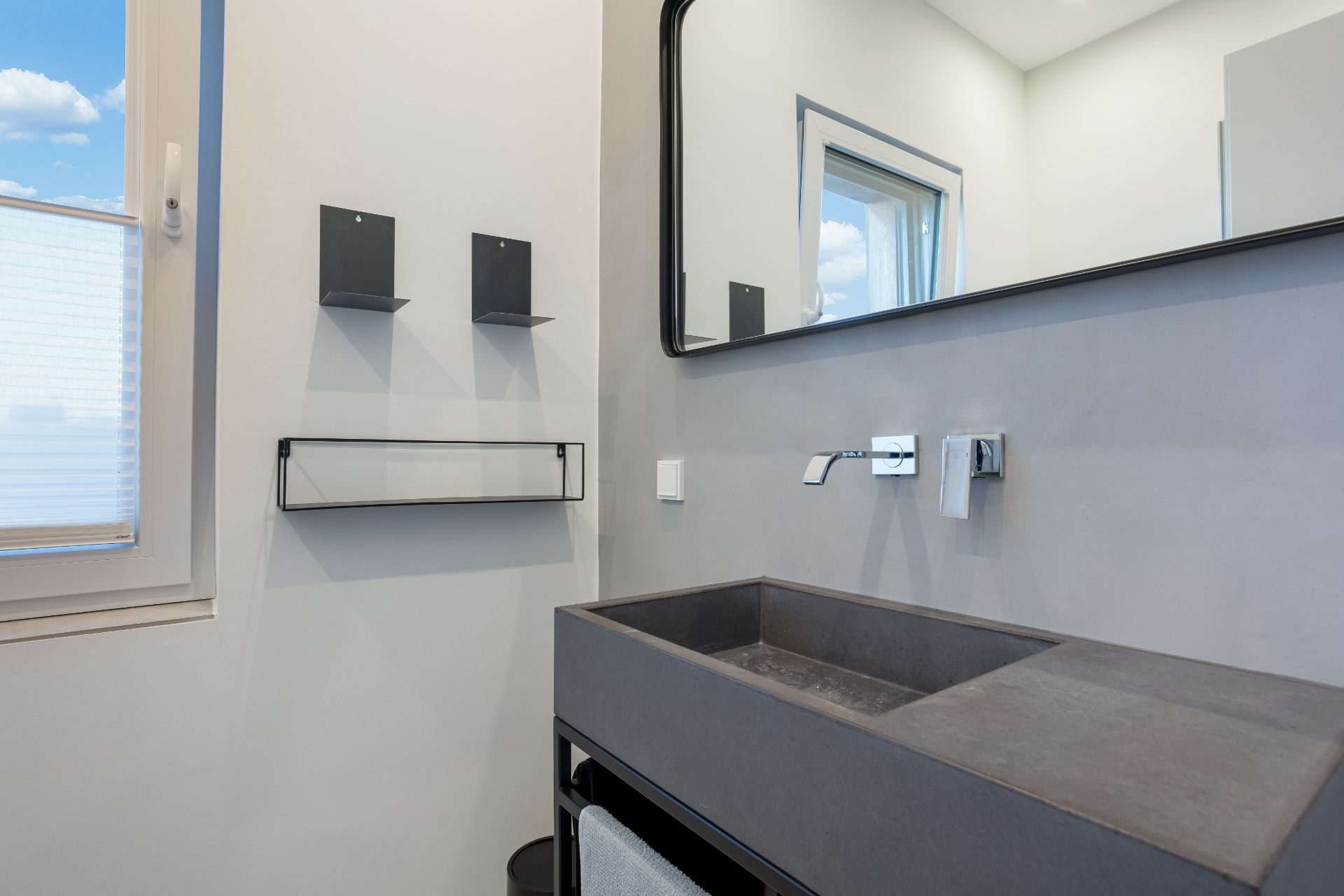 Modernes Badezimmer mit rechteckigem Waschbecken, großem Spiegel und Fenster.