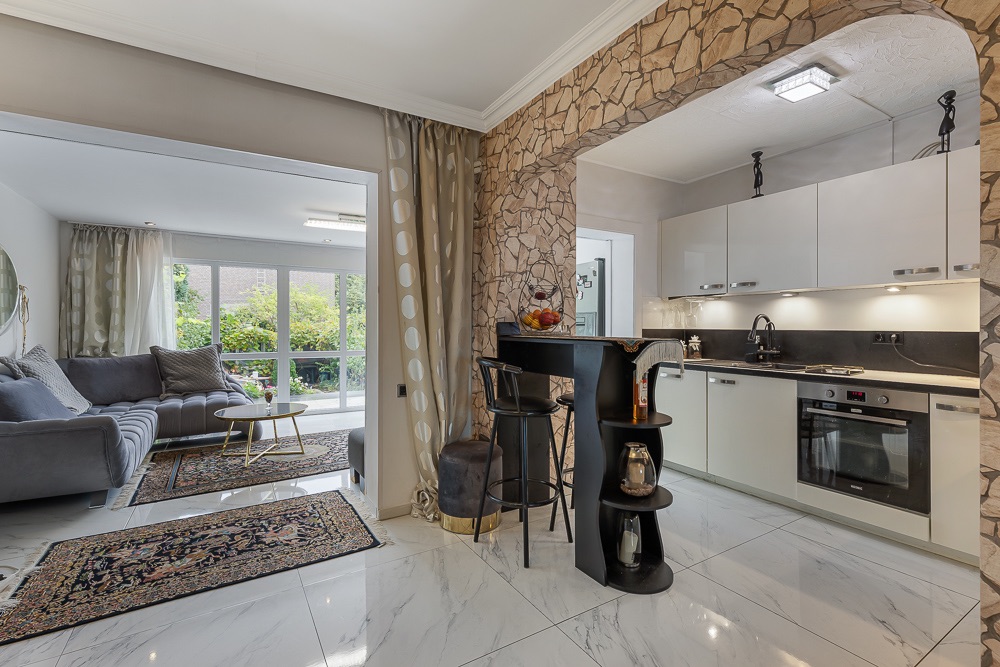 Moderne offene Küche mit Bartresen und angrenzendem Wohnzimmer mit großen Fenstern.