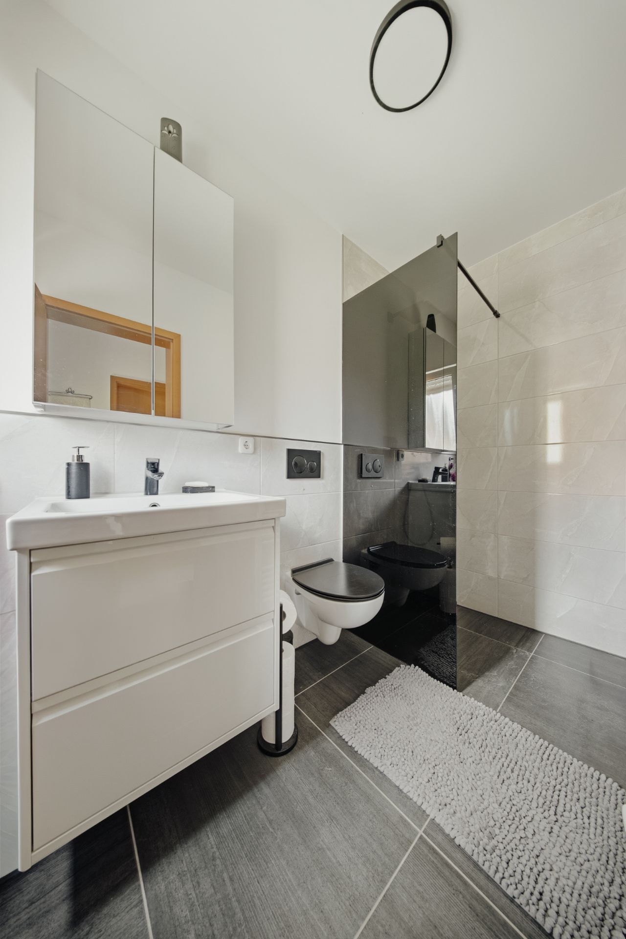 Modernes Badezimmer mit Waschtisch, Spiegel, Hänge-WC und begehbarer Dusche.
