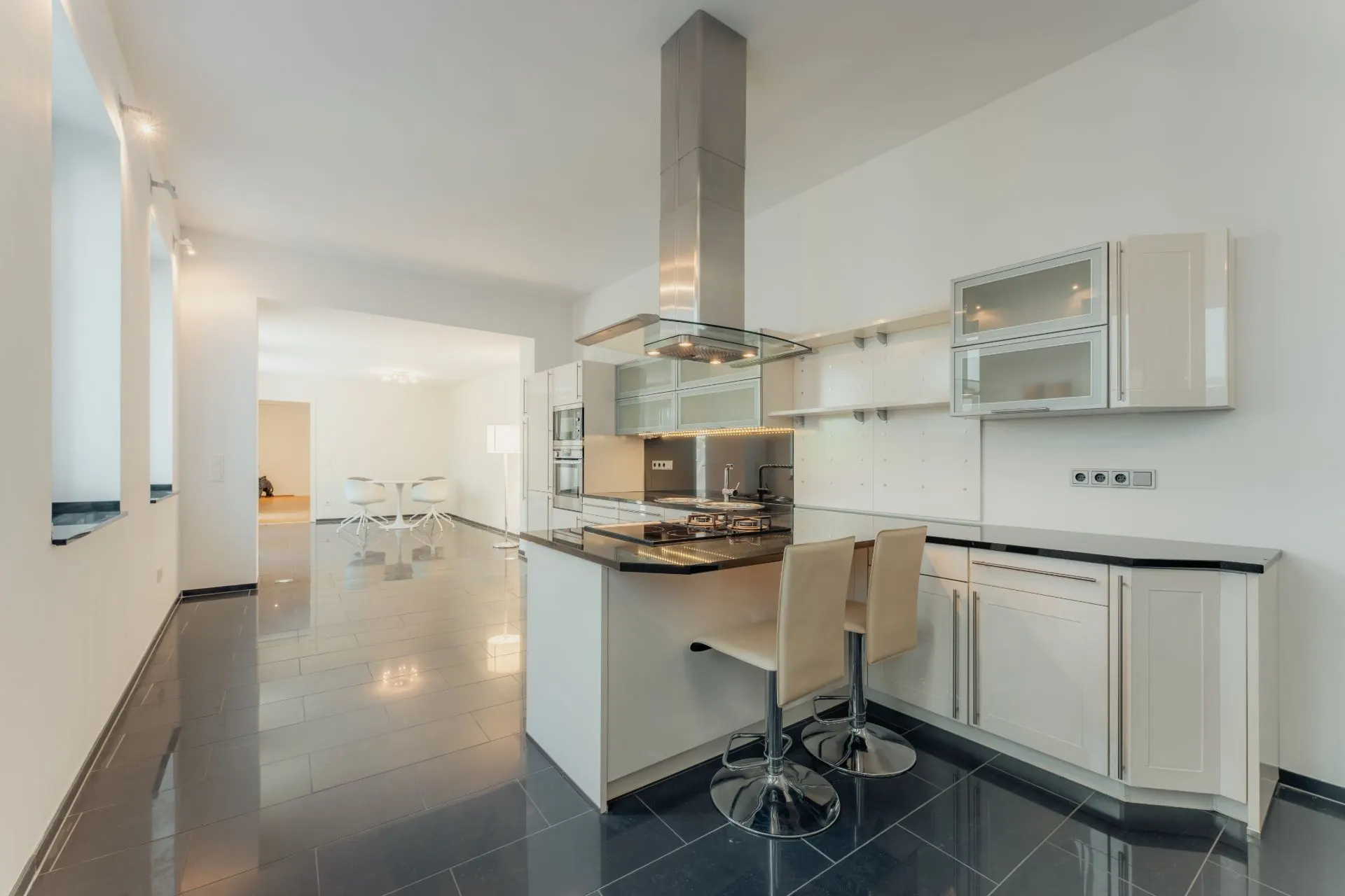 Moderne Küche mit Kochinsel, Barhockern und angrenzendem Essbereich in heller Wohnung.