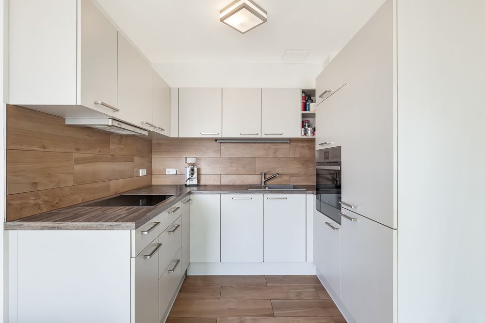 Moderne Küche mit weißen Schränken, Holzboden und Holzwandverkleidung.