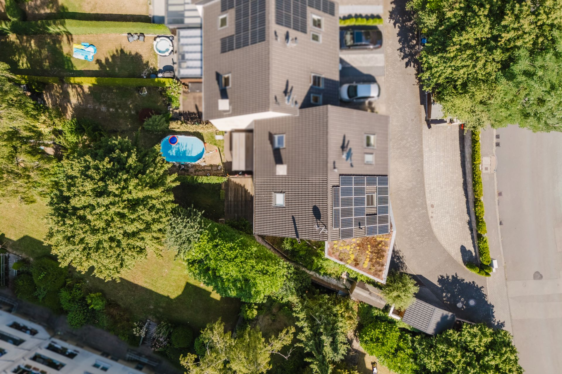 Luftaufnahme eines Hauses mit Solarpanels und Garten mit kleinem Pool.