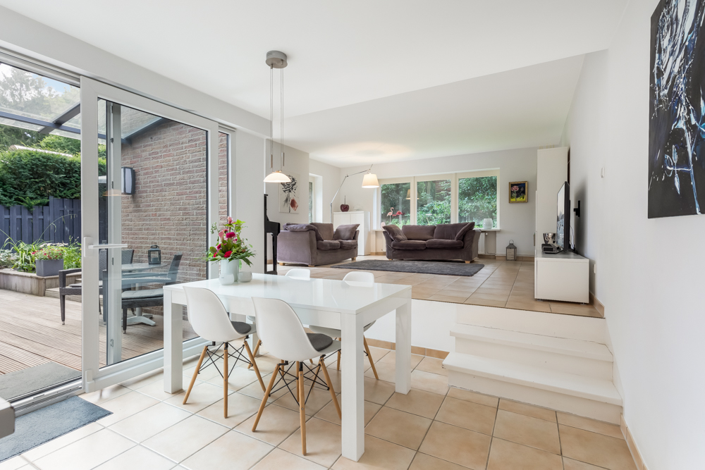 Helles Wohnzimmer mit Essbereich, Tisch mit Stühlen und Zugang zur Terrasse, Sofa und Fernseher.
