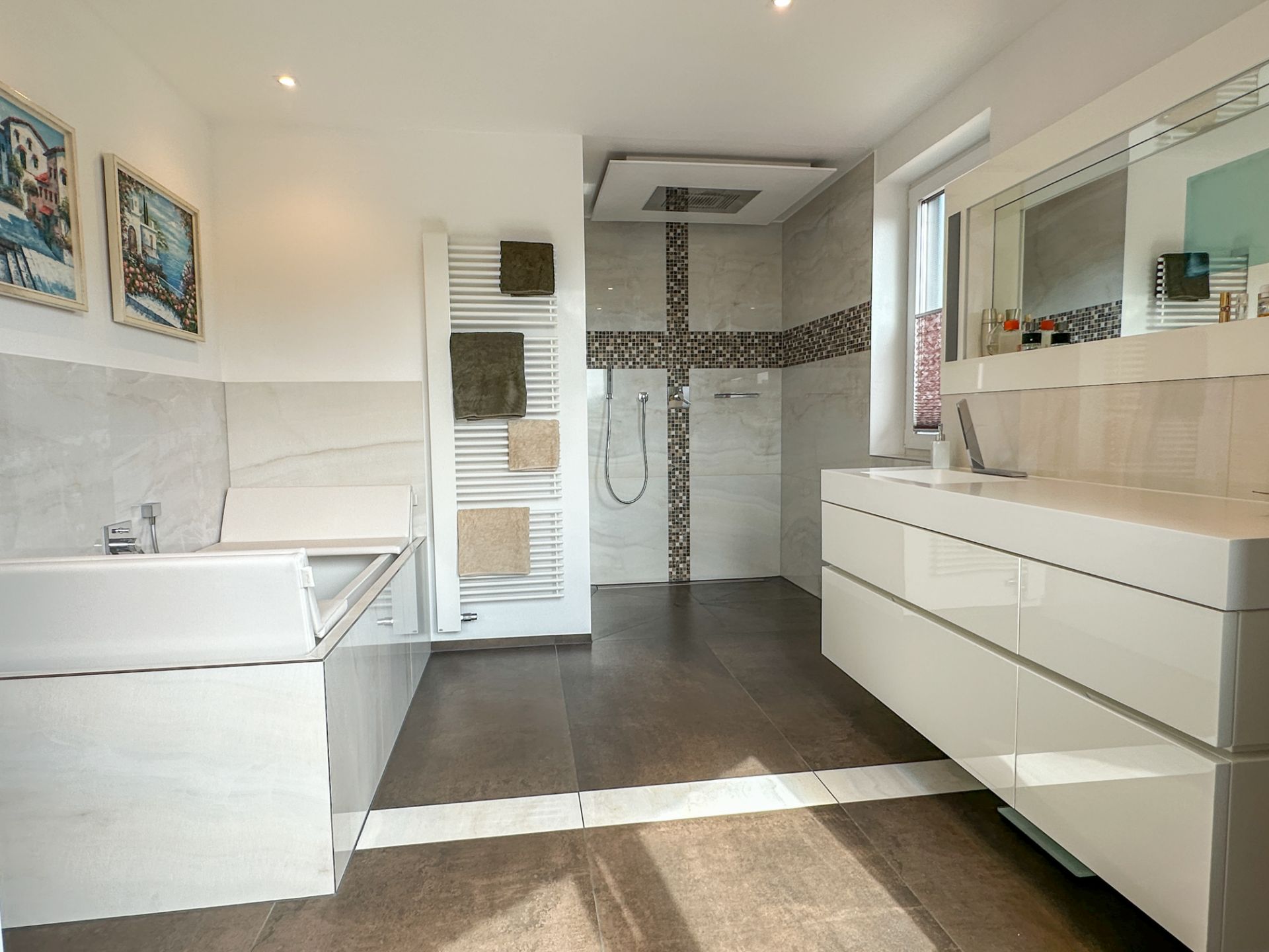Modernes Badezimmer mit Badewanne, Dusche, Waschtisch, Handtuchheizkörper und Spiegel.