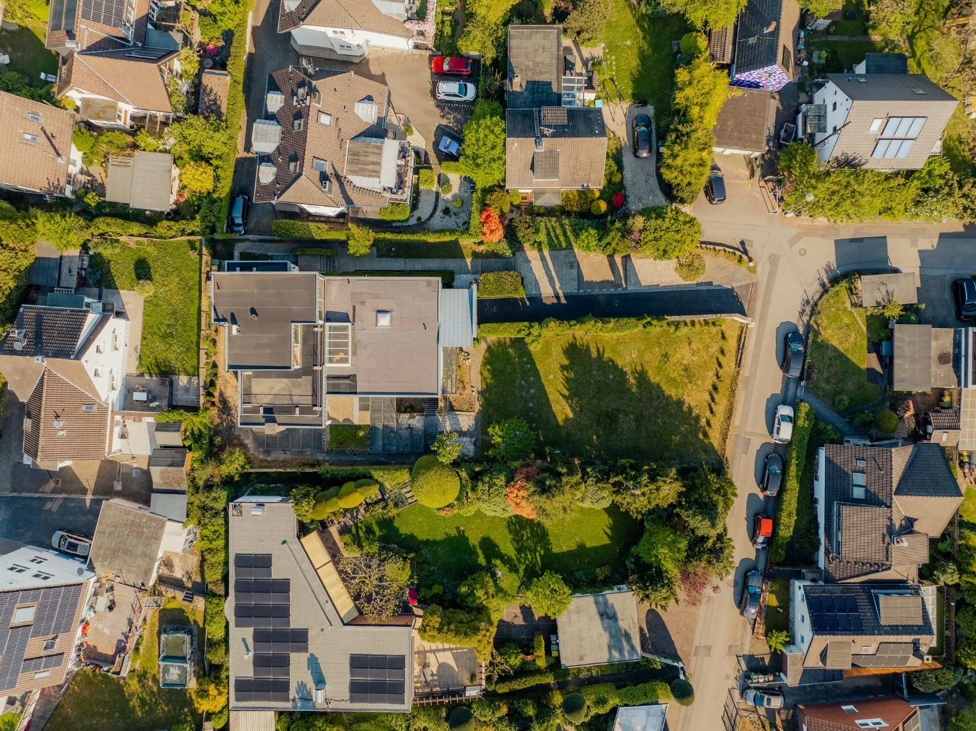 Luftaufnahme von Wohnhäusern mit Gärten und Straßen in einem Wohngebiet.