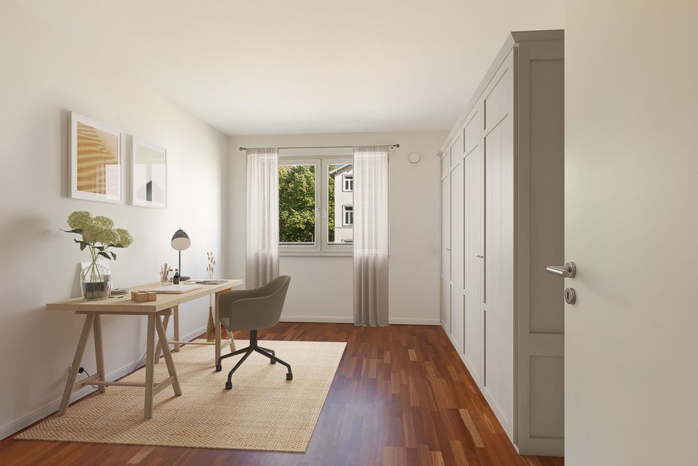 Helles Arbeitszimmer mit Schreibtisch, Stuhl, großem Schrank und Fenster mit Blick ins Grüne.