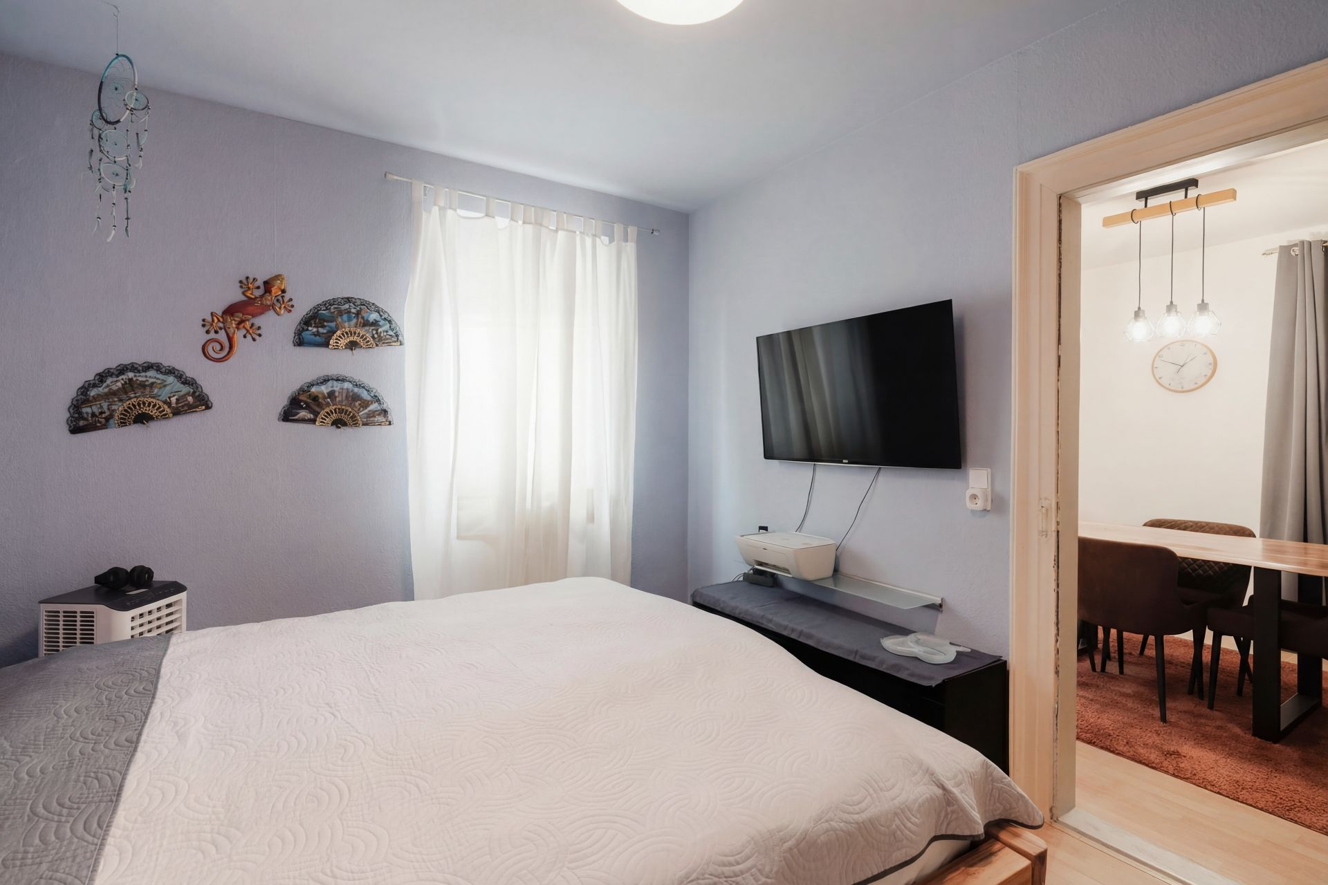 Schlafzimmer mit Doppelbett, Wanddekoration, Fernseher und Blick ins Esszimmer.
