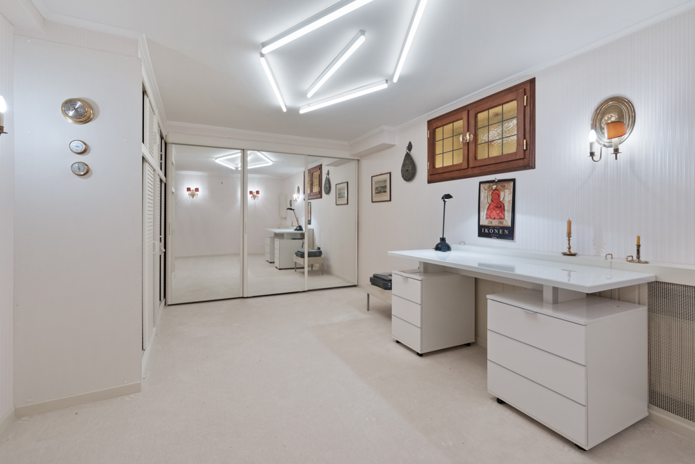 Helles Arbeitszimmer mit weißem Schreibtisch, Spiegel-Schiebetüren und Wanddekoration.