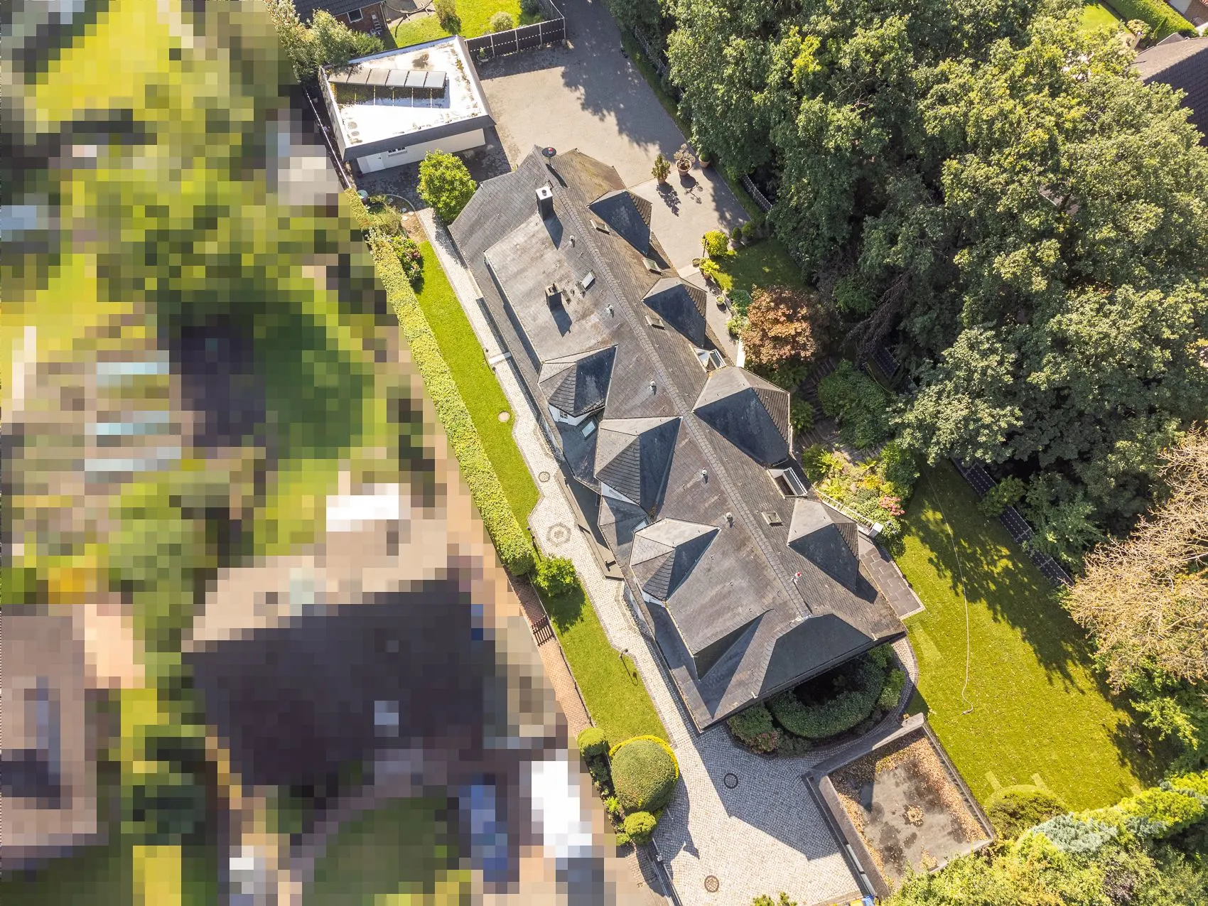 Luftaufnahme eines großen Wohnhauses mit Garten und umliegenden Bäumen.