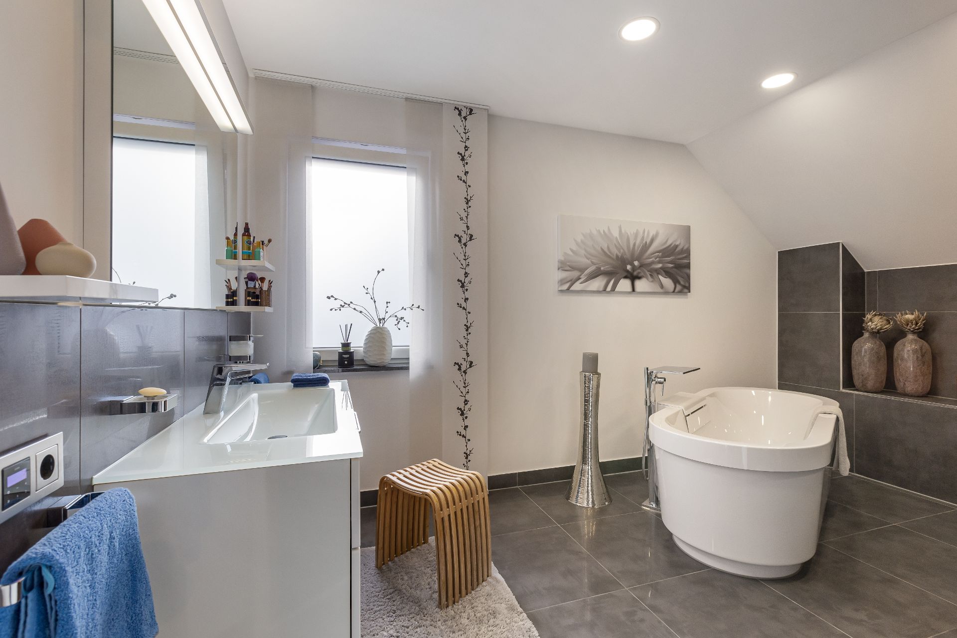 Modernes Badezimmer mit freistehender Badewanne, Waschbecken und großer grauer Fliese.