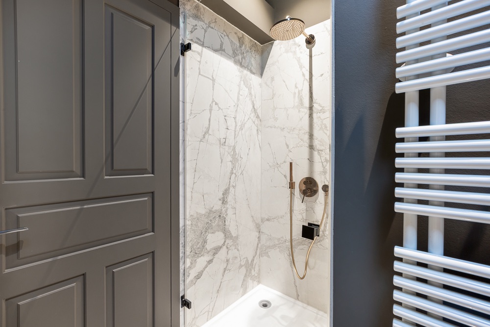 Moderne Dusche mit Marmorfiesen, Regendusche und Handtuchheizkörper.