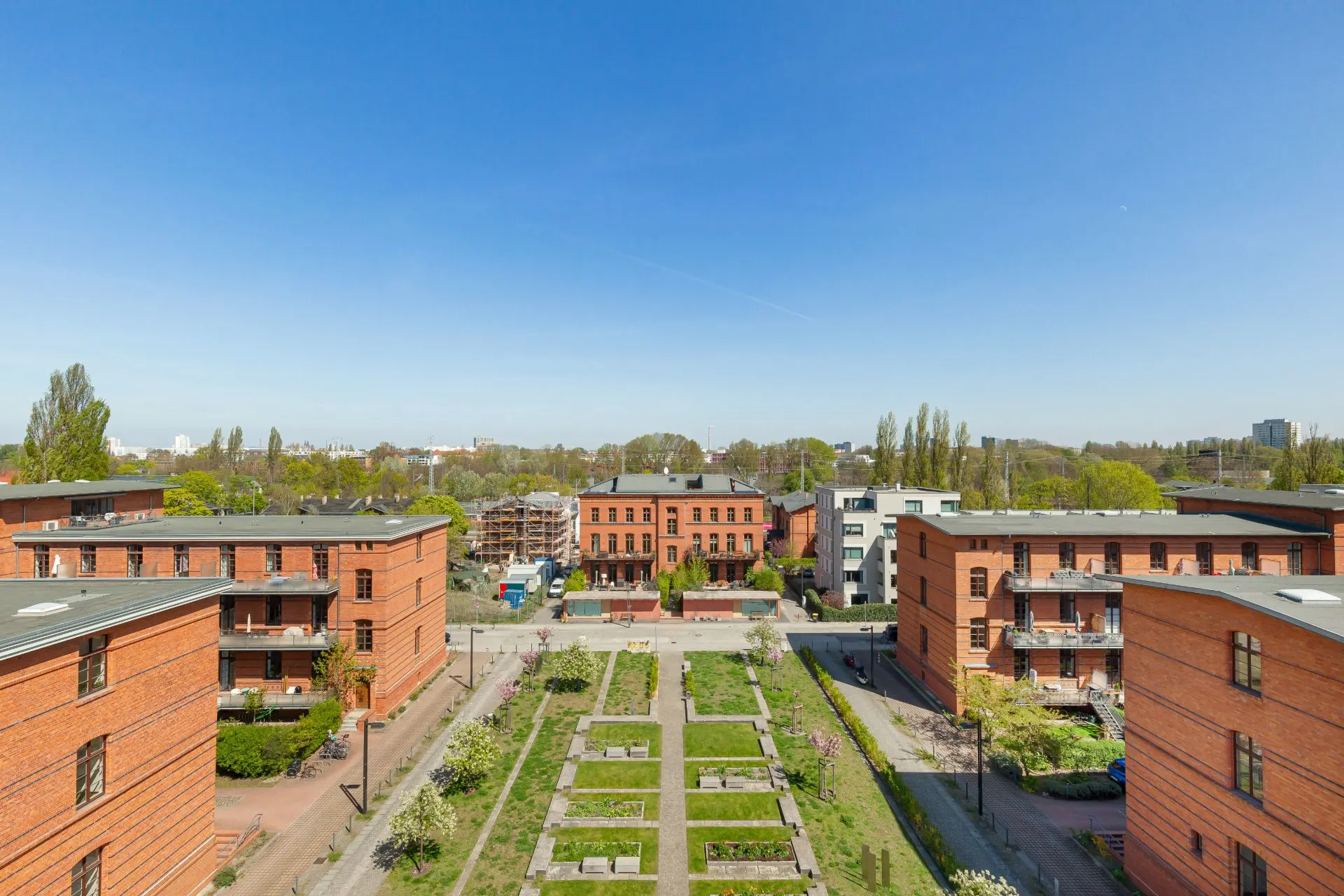 Blick auf rote Wohnhäuser mit einem großen, rechteckigen Garten in der Mitte.
