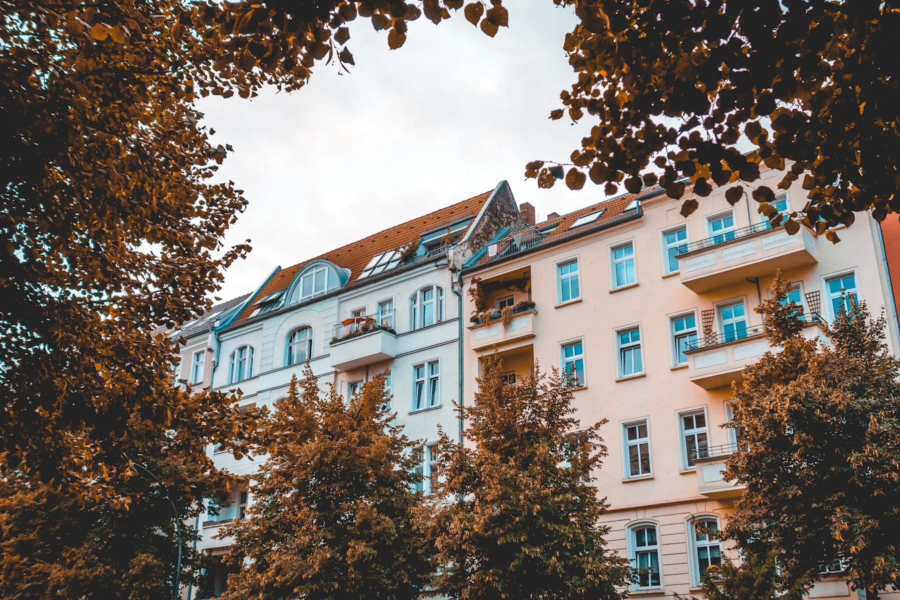 Mehrstöckige Wohngebäude mit Balkonen, umgeben von Bäumen.