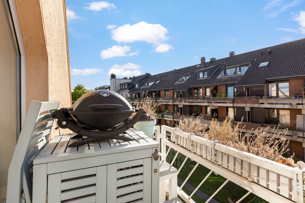 Kleiner Balkon mit Grill und Sicht auf ein Wohnhaus gegenüber.