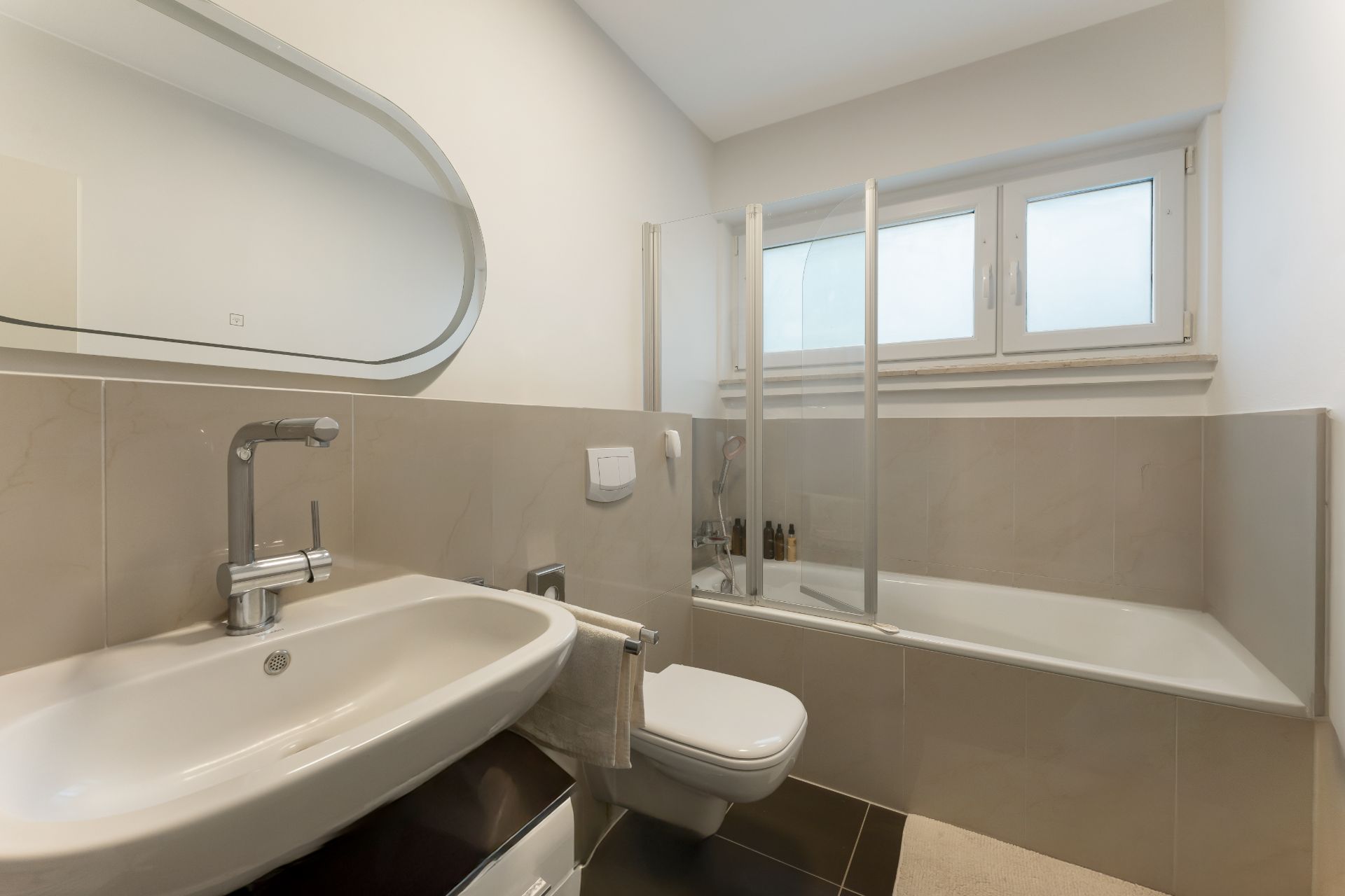 Modernes Badezimmer mit Waschbecken, Wandtoilette, Badewanne und großem Fenster.