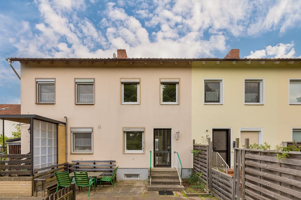 Vorderansicht eines Reihenhauses mit Gartenmöbeln und Terrasse im Eingangsbereich.