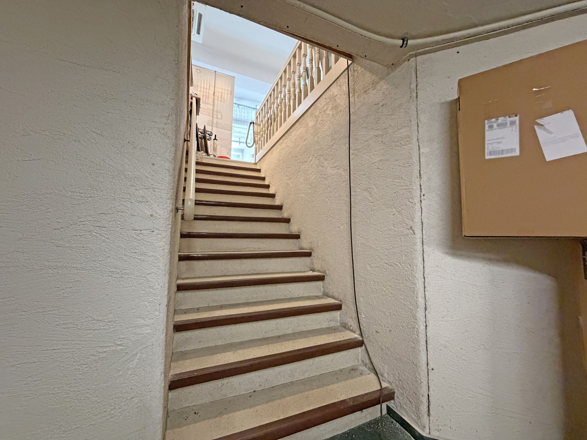 Treppe in einem Flur mit Handlauf und Briefkasten an der rechten Wand.