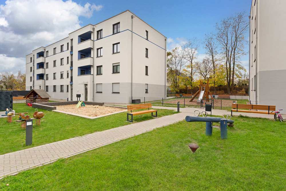Innenhof mit Spielplatz, Sandkasten, Bänken und modernen Wohngebäuden.