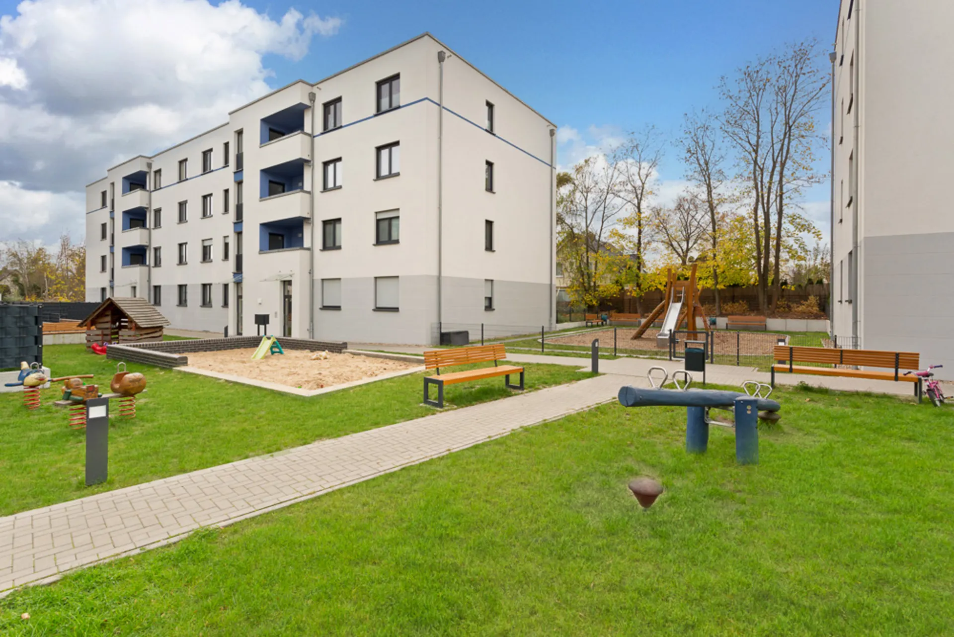 Innenhof mit Spielplatz, Sandkasten, Bänken und modernen Wohngebäuden.