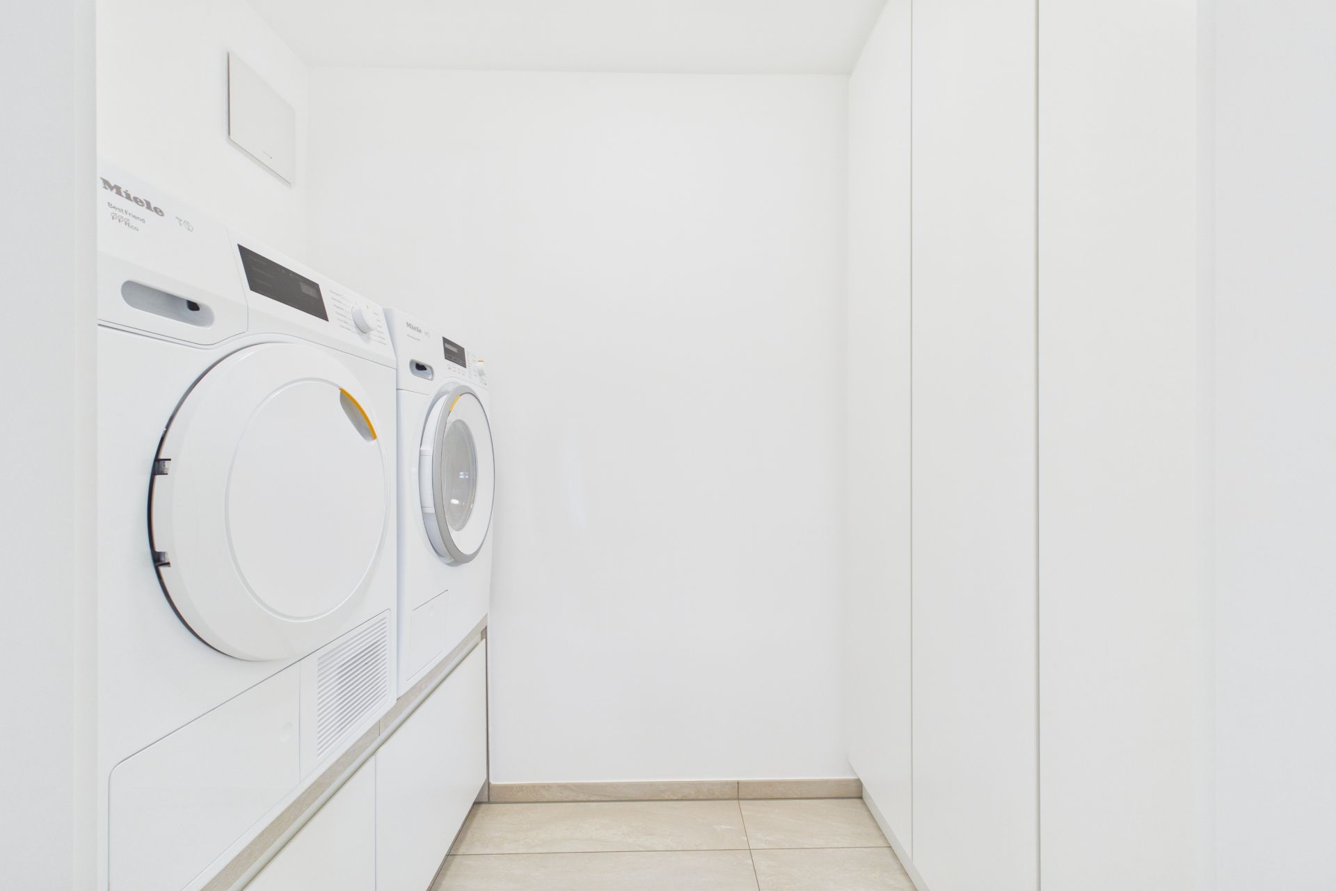 Heller Hauswirtschaftsraum mit Waschmaschine und Trockner nebeneinander.