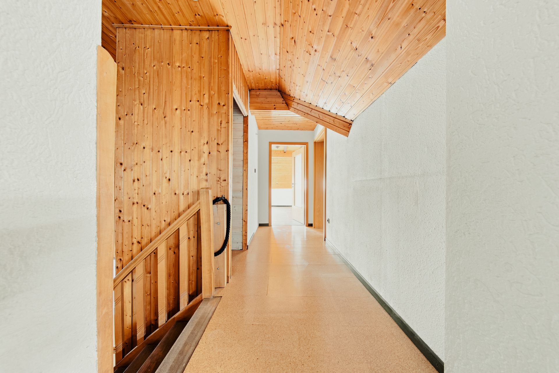 Heller Flur mit Holzdecke und Treppe, mehrere Türen führen zu anderen Räumen.