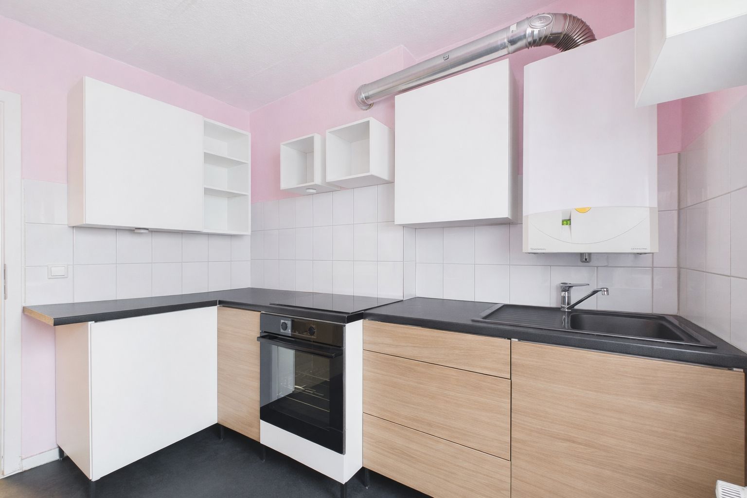 Moderne Einbauküche mit weißen und holzfarbenen Schränken, Backofen und Spüle.