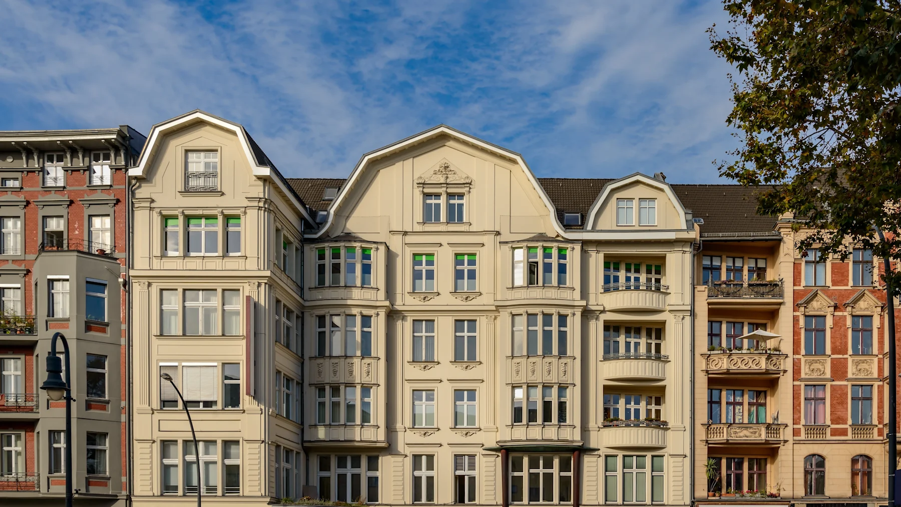 Mehrstöckiges Wohnhaus mit hellem, verzierten Fassadendekor und vielen Fenstern.