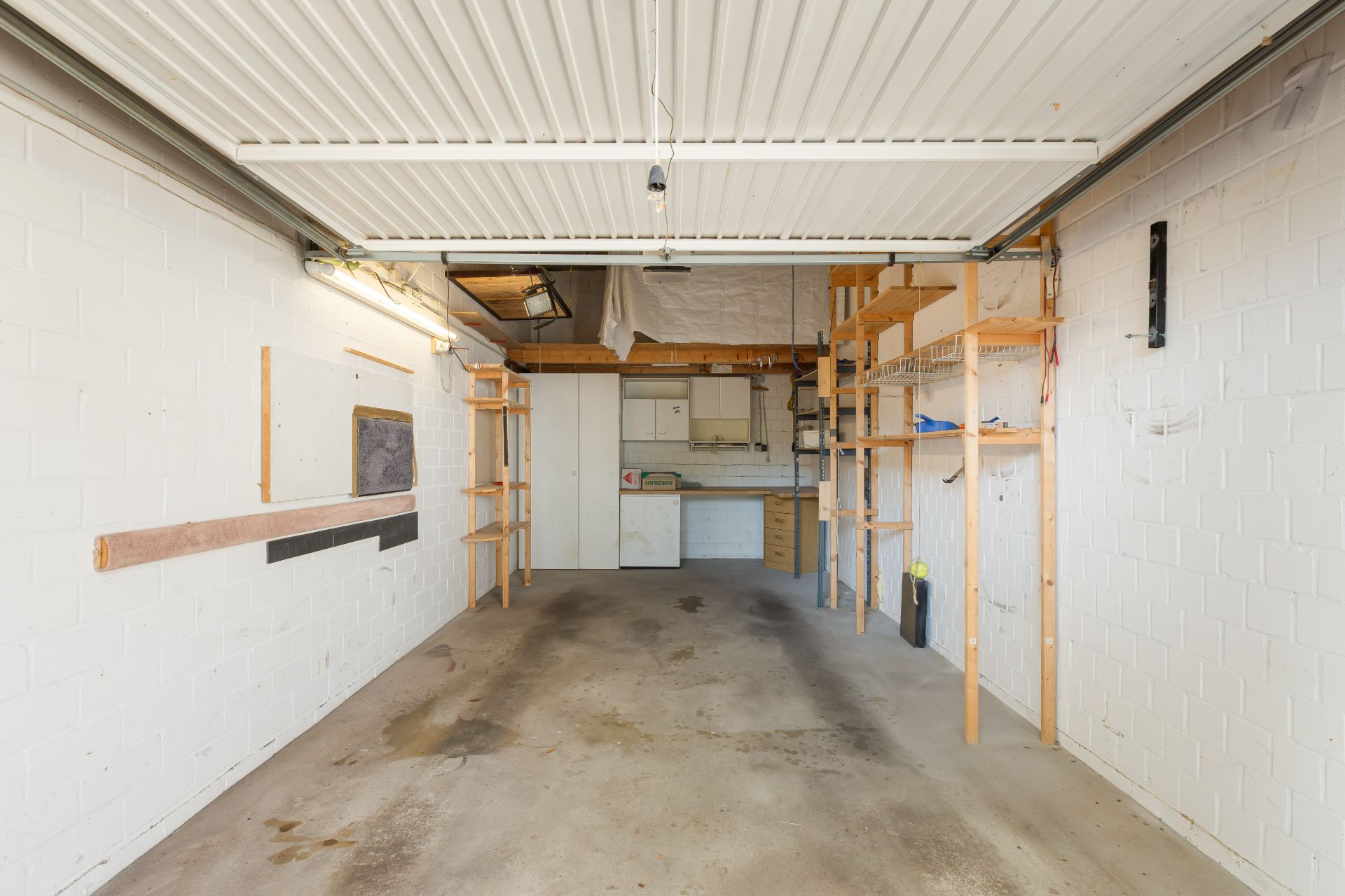 Leere Garage mit Regalen und Werkbank an der Rückwand.