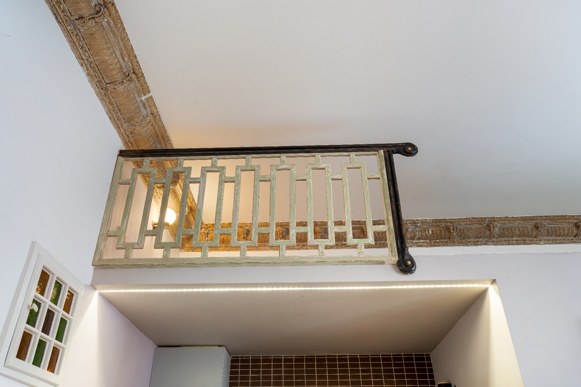 Ein kleiner Balkon mit dekorativem Geländer im Innenraum über einer Küchenzeile.