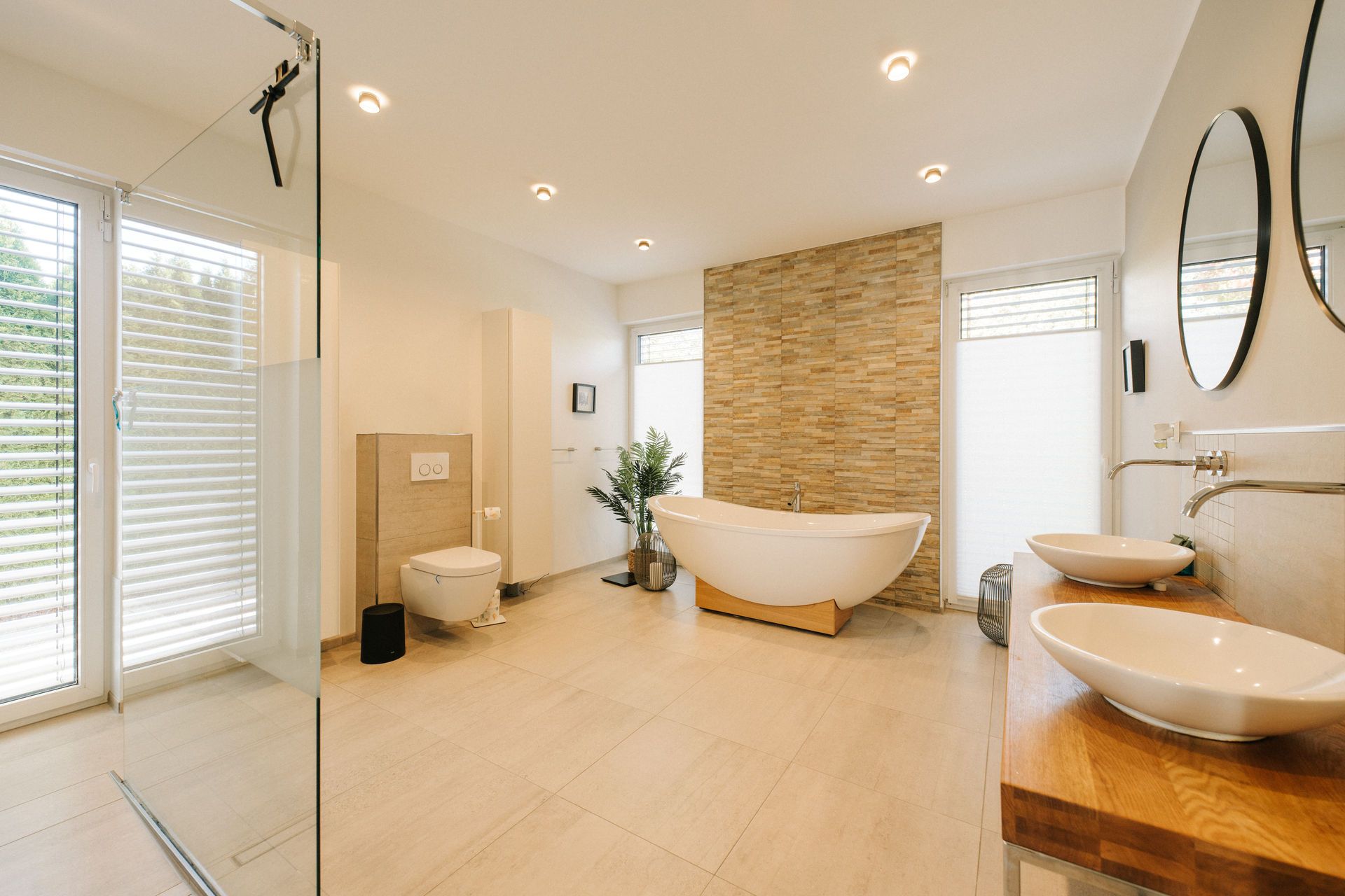 Modernes, helles Badezimmer mit freistehender Badewanne, zwei Waschbecken und großer Dusche.