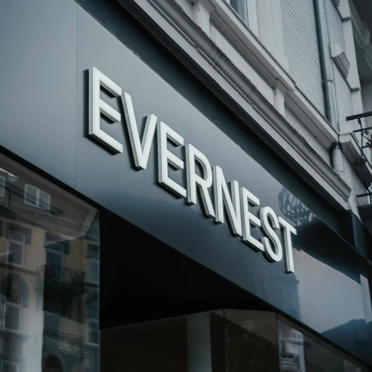 Schwarzes Schild mit weißem Schriftzug 'EVERNEST' an einer Gebäudefassade.