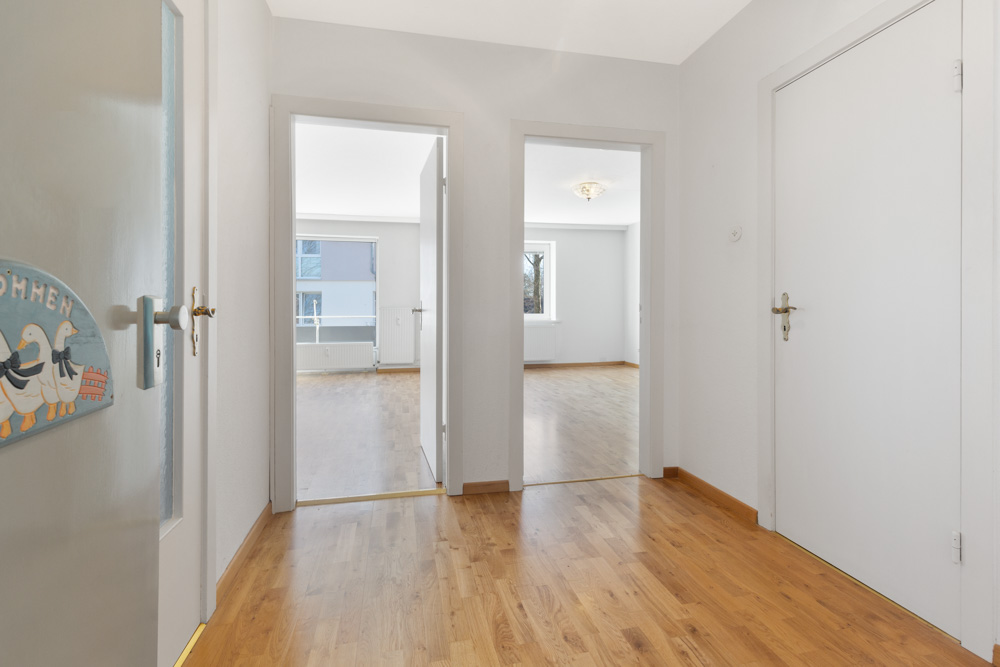 Heller Flur mit Holzboden, mehreren Türen und Blick in zwei angrenzende Räume.