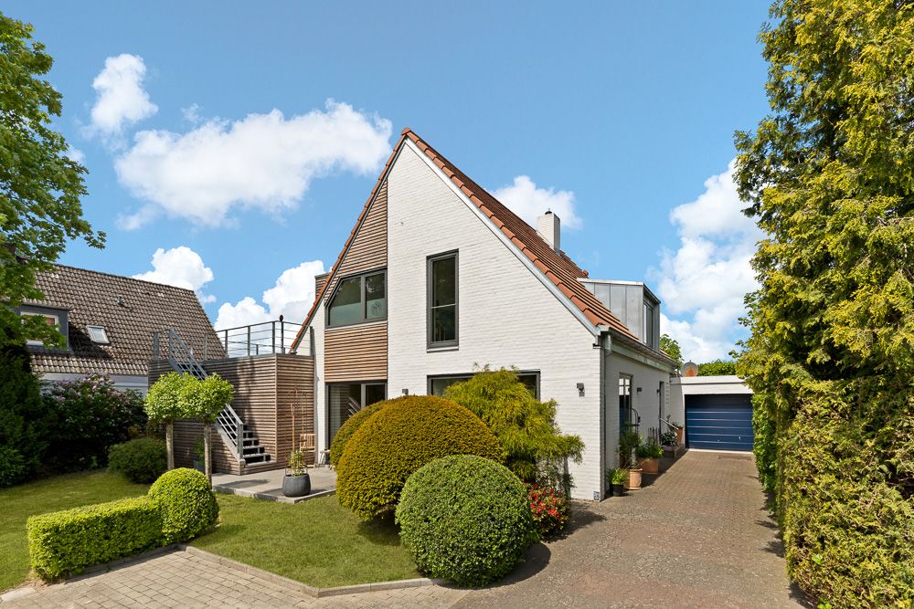 Modernes Einfamilienhaus mit Satteldach, großer Fensterfront und gepflegtem Garten vor der Tür.