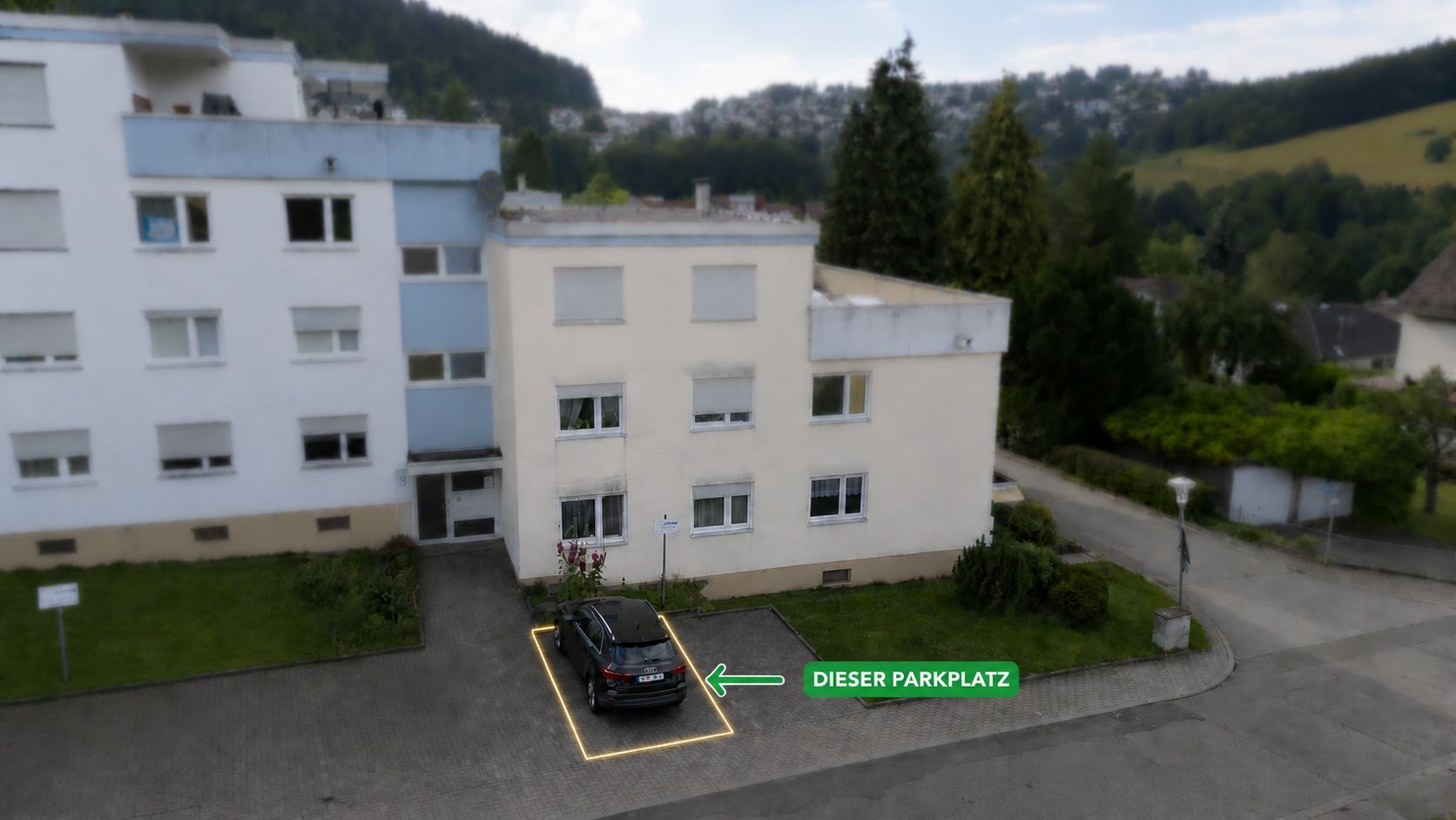 Wohnhaus mit markiertem Parkplatz und schwarzem Auto davor.