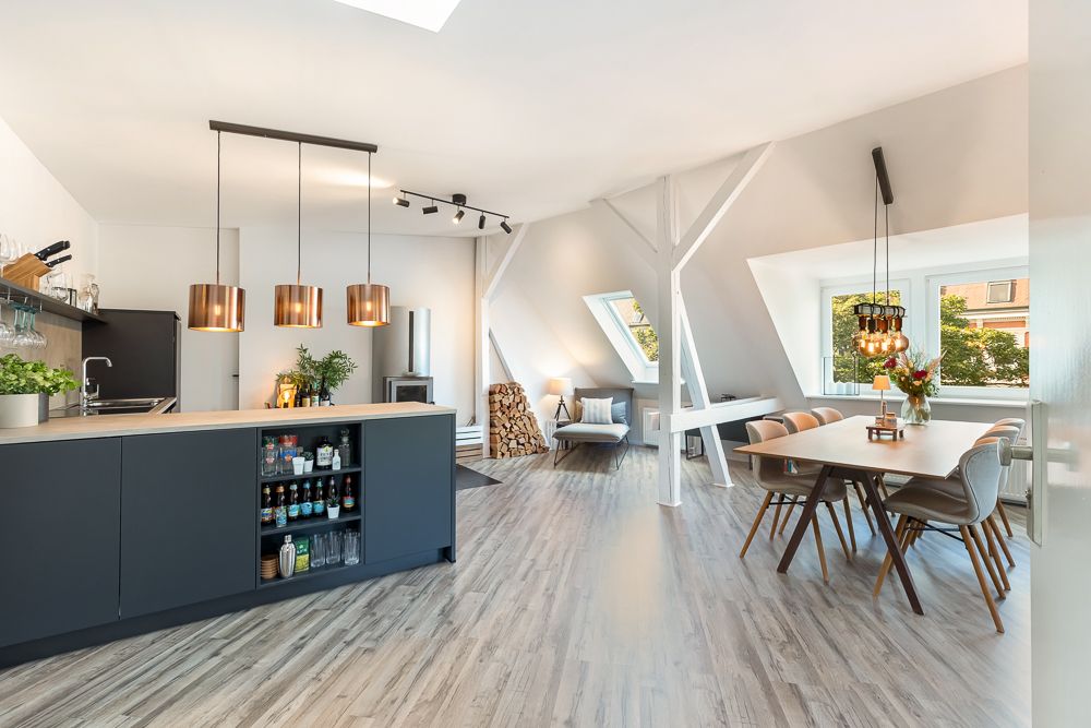 Moderne offene Küche mit Essbereich und großen Fenstern in einer hellen Wohnung.