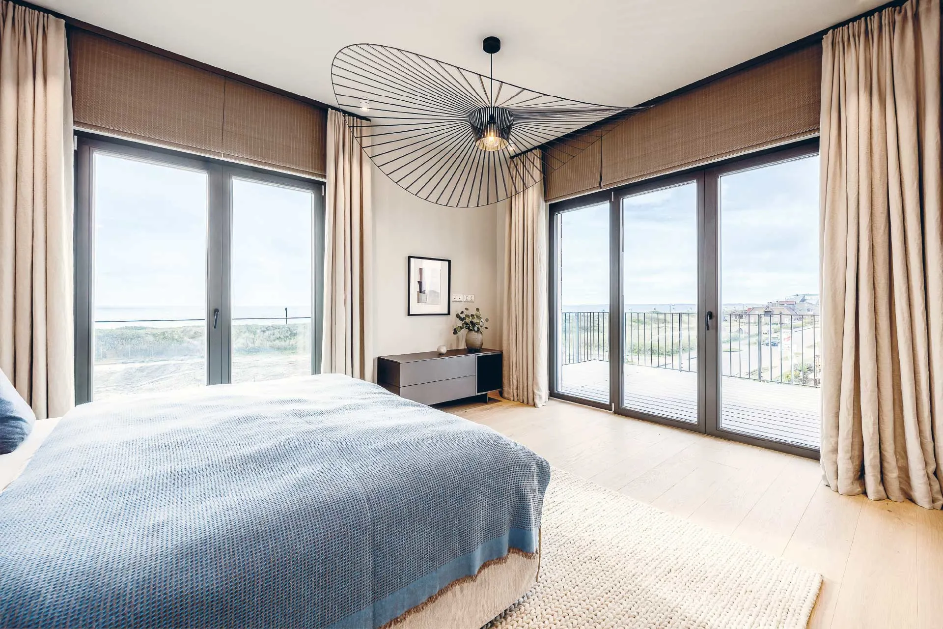 Helles Schlafzimmer mit großem Bett, modernen Fenstern und Zugang zum Balkon.