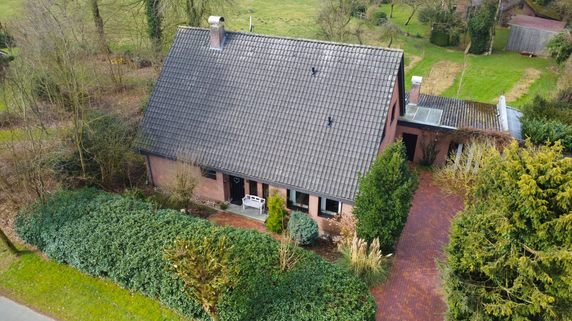 Luftaufnahme eines Hauses mit Satteldach, Vorgarten und gepflasterter Einfahrt.
