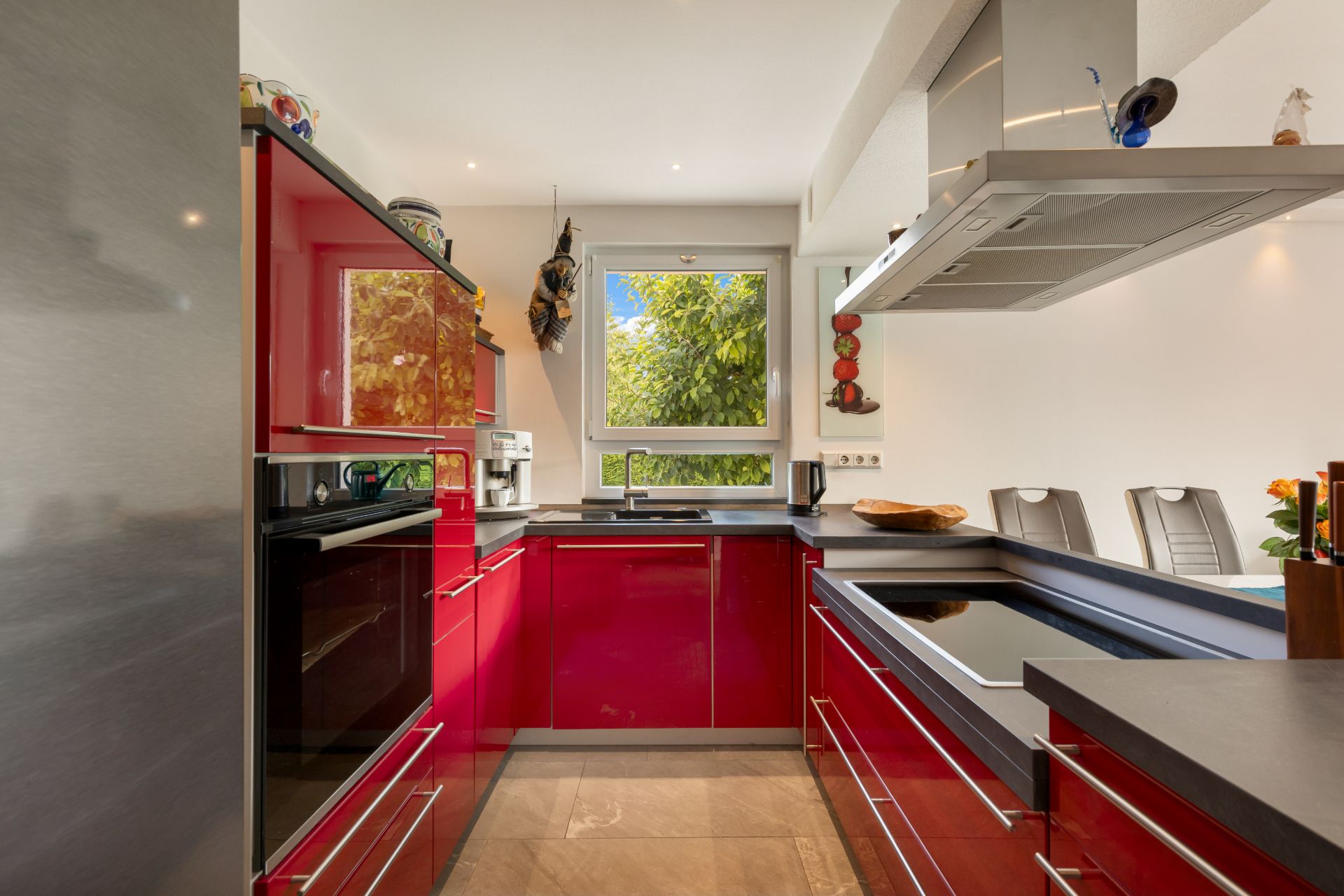 Moderne Küche mit roten Hochglanzschränken, Fenster und Kochinsel.