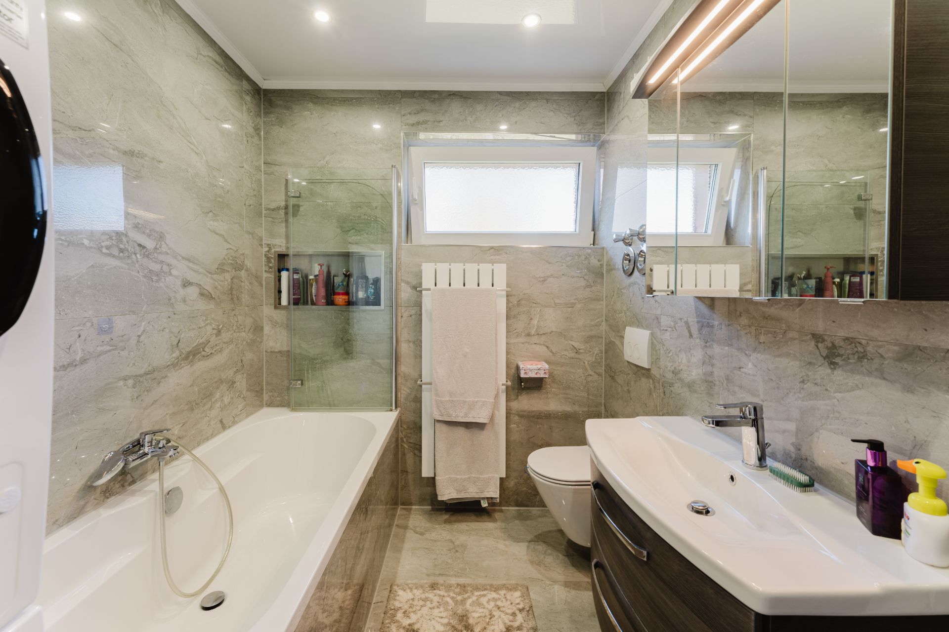Modernes Bad mit Badewanne, Doppelwaschbecken, WC, Handtuchheizung und Spiegelschrank.